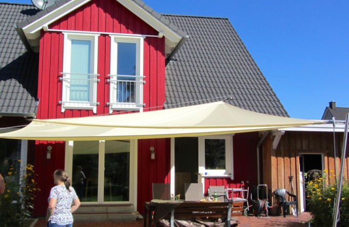 Sonnensegel manuell Weyhe 2M / 2 W in elfenbein vor roten Haus