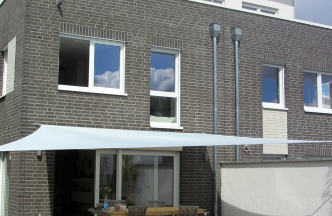Sonnensegel feststehend Köln 2M / 2W II. weißes Segel vor einem grauen Haus